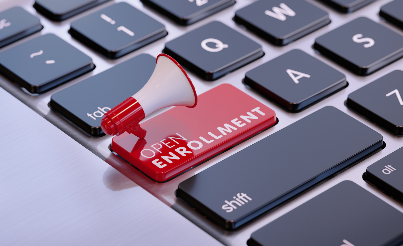 Red megaphone sitting on open enrollment written computer keyboard. Horizontal composition with copy space.