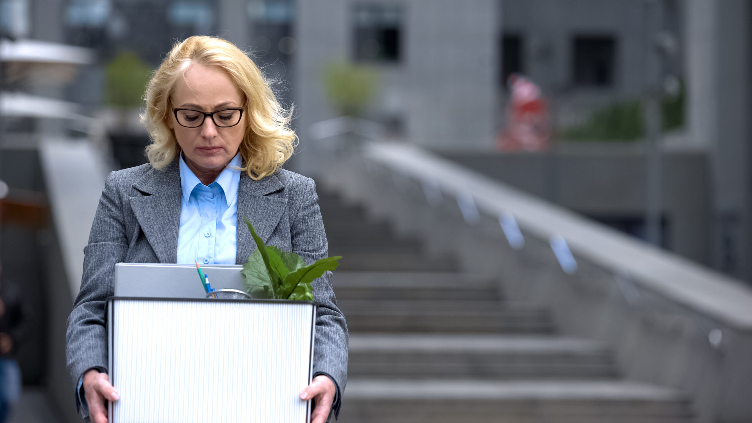 depressed woman worker who just resigned carrying a box of office materials