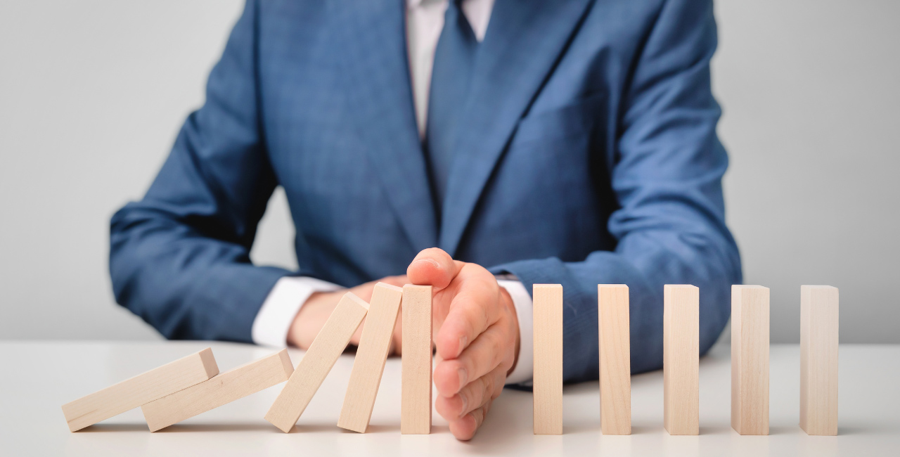 A business professional preventing a row of dominoes from falling down