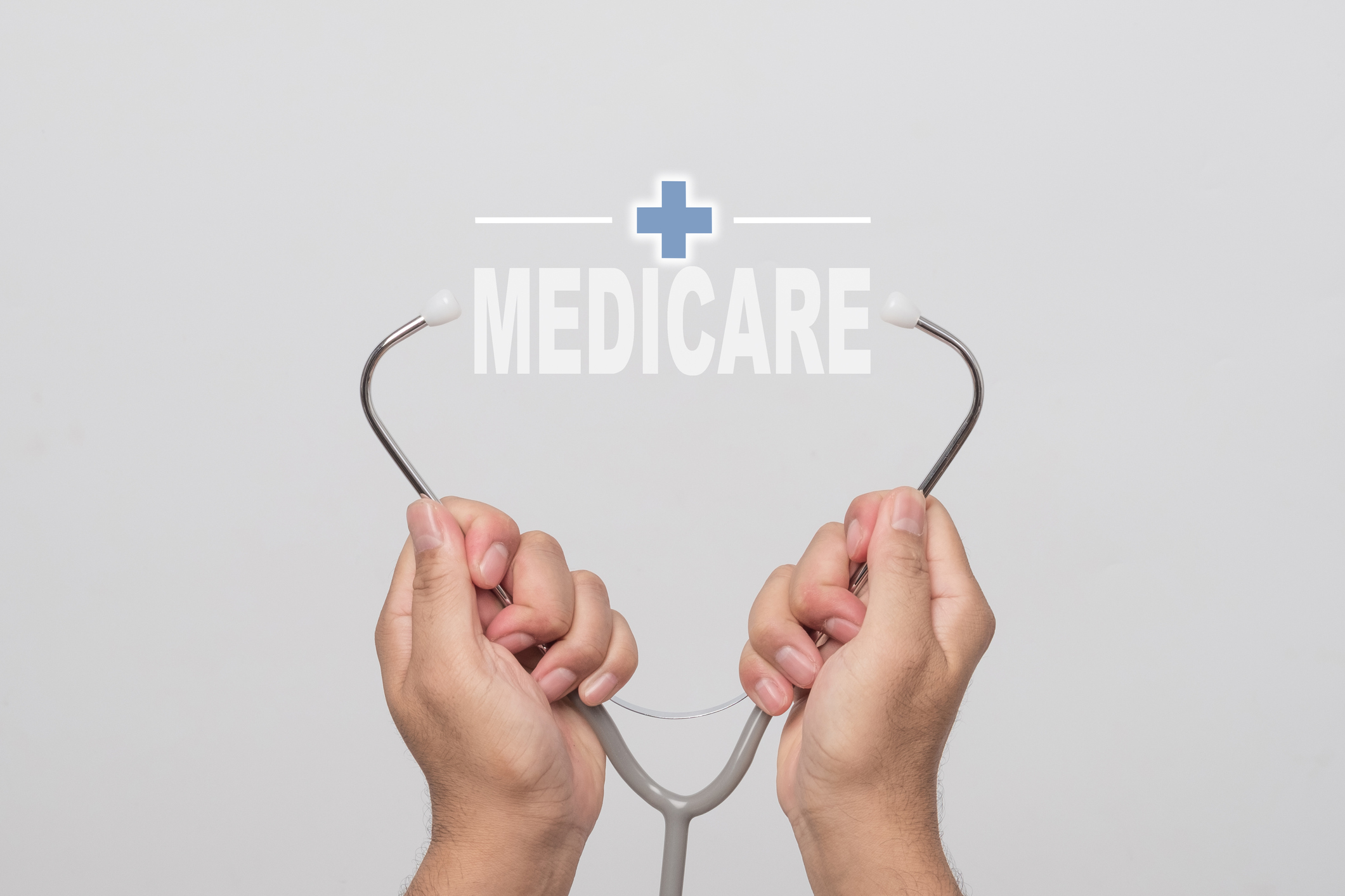 Hands holding a stethoscope and word "MEDICARE" on gray background. concept Healthy.