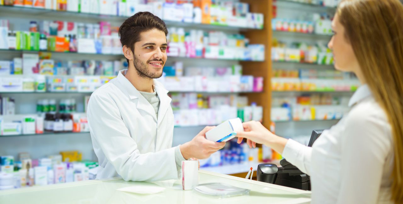 A pharmacist handing medication to a customer at a pharmacy