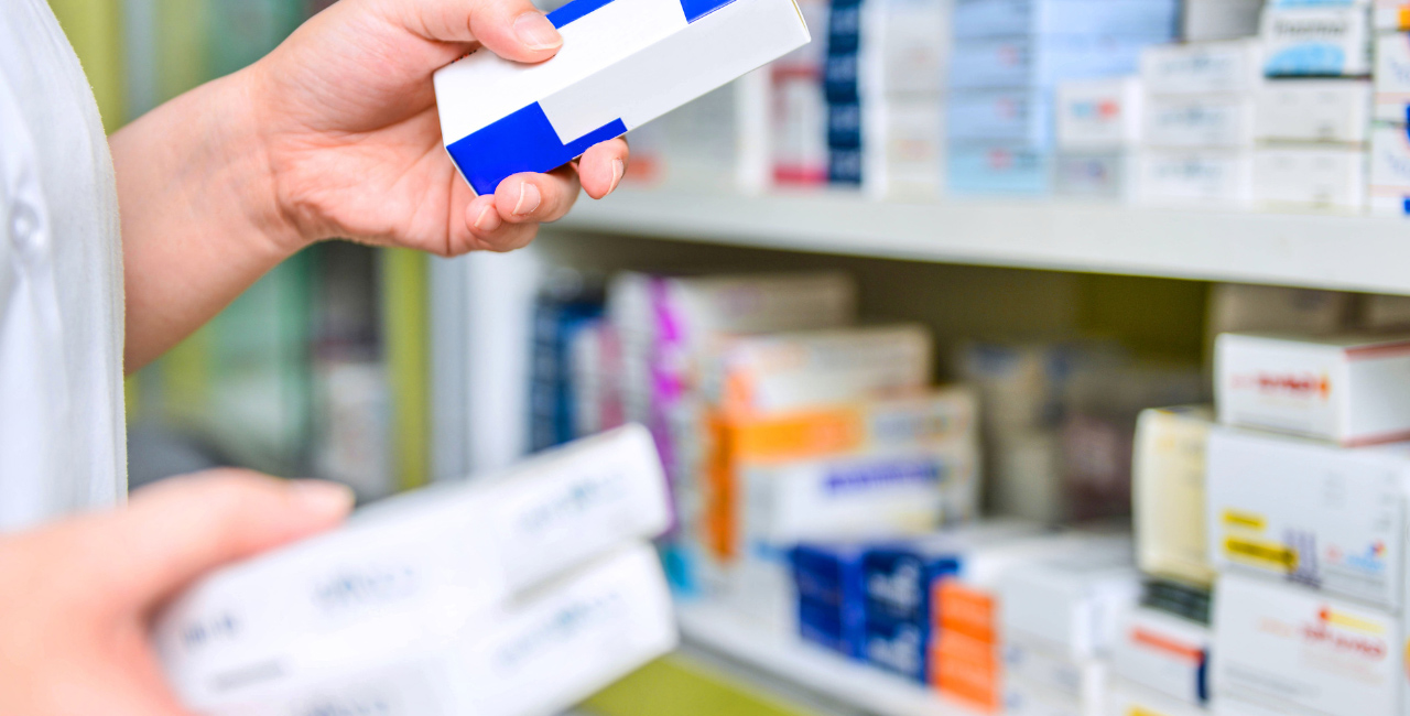A pharmacist examining medication on a shelf at a pharmacy